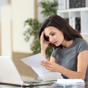A woman with a laptop and documents, appearing to be concentrated on Workers’ Comp Denials - Leep Tescher Helfman and Zanze