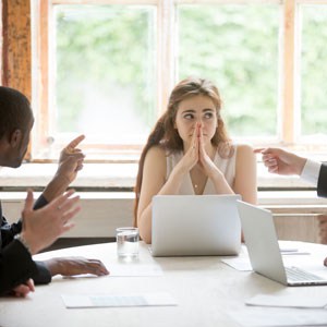 Three individuals sitting at a table laptops discussing loss in the workplace - Leep Tescher Helfman and Zanze