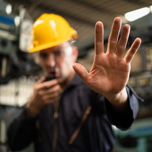 A construction worker wearing a hard hat raises a hand to stop someone - Leep Tescher Helfman and Zanze