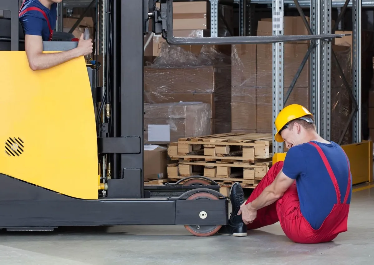 Warehouse worker injured near a forklift after a workplace accident, illustrating a case involving a forklift accident lawyer and workers' compensation claim.